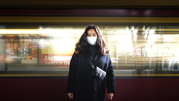 Eine Frau steht mit Maske in einer U-Bahn-Station